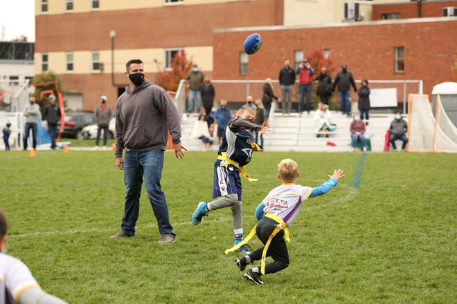 Players compete in the Newton Area Flag Football League while a coach looks on.