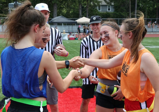 Team Blue/Red captains Devon Morton and Natalie Bovie shake hands with Team Orange/White captains Riley Boyle and Kady Bedard while refs Will Madden and Anthony Perez look on.