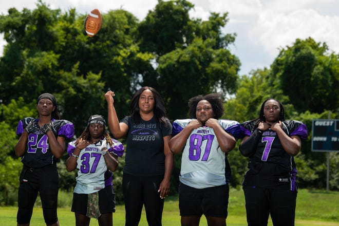 The women's football team, 'Music City Mizfits' Rodneika Crutcher (37), MJ Johnson (7), Jennika Watts (24), and Gwendolyn Hardison (87) pose together with their coach Donita Hines at the Lighthouse Christian football field in Antioch, Tenn., Friday, July 15, 2022. 