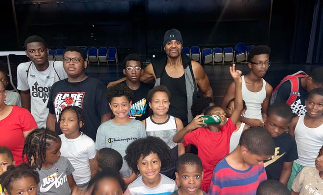 Kevin Lawrence, center, poses in the Poughkeepsie High School auditorium alongside a group of local kids enrolled in a local youth football camp. Lawrence, a Poughkeepsie native, was a guest speaker on Thursday.