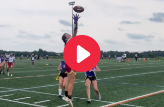 A girl makes a one-handed catch in a flag football game.