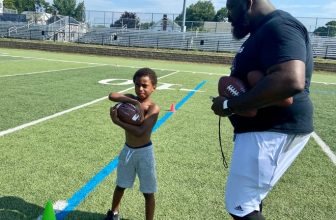 A young football camp participant is instructed during a drill by coach Isaiah Majurie on Thursday at the Poughkeepsie High School football field.