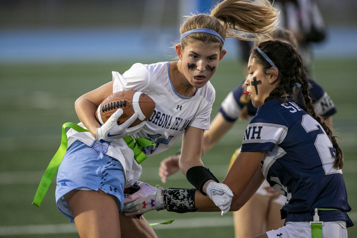 CdM's Ellie Liberto has her flag pulled by Newport Harbor's Maia Helmar during the Battle of the Bay game Wednesday.