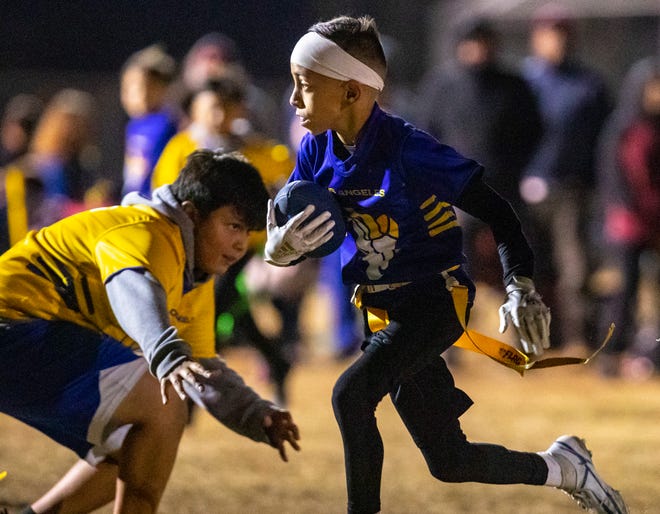 Amelia Earhart Elementary's Kaleb Elms, 11, runs the ball narrowly avoiding a defender during the DSUSD Elementary Flag Football League Championships at Colonel Mitchell Paige Middle School in La Quinta, Calif., Friday, Dec. 9, 2022. 