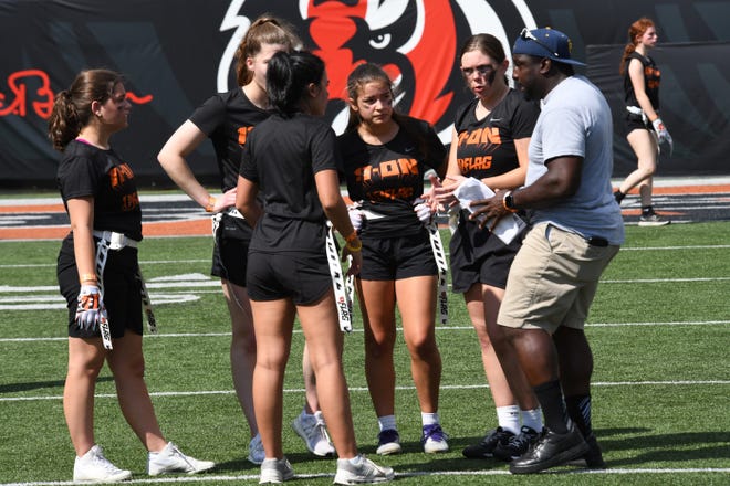 Coach goes over the next play call with his players at the girls flag football kickoff jamboree sponsored by USA Flag Football and the Cincinnati Bengals at Paycor Stadium, Sept. 30, 2023.
