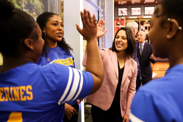 Juliana Zavala, senior manager of elementary sports for Chicago Public Schools, high-fives players Morgan Ellis as she speaks with players and Head Coach Erin Pruitt from Simeon Career Academy after a press conference announcing the sanctioning of girls flag football at Halas Hall in Lake Forest on Feb. 14, 2024. (Eileen T. Meslar/Chicago Tribune)