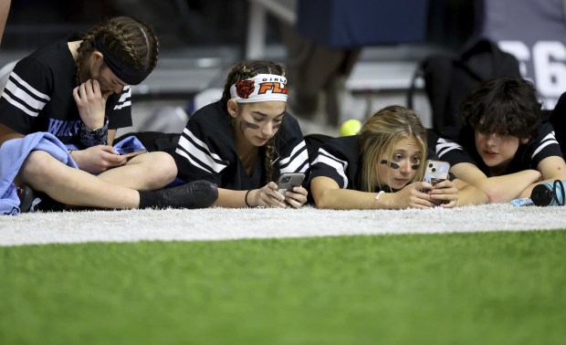 Willowbrook High School players relax while looking at their phones...